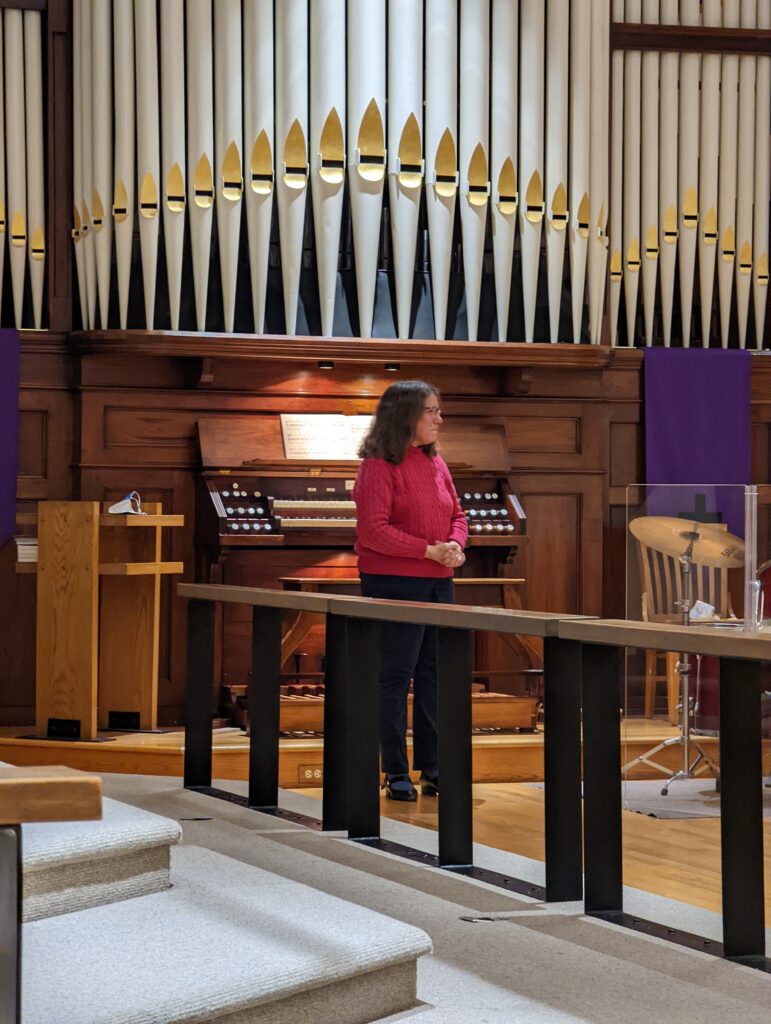 Cheryl Drewes standing in front of organ bench facing audience