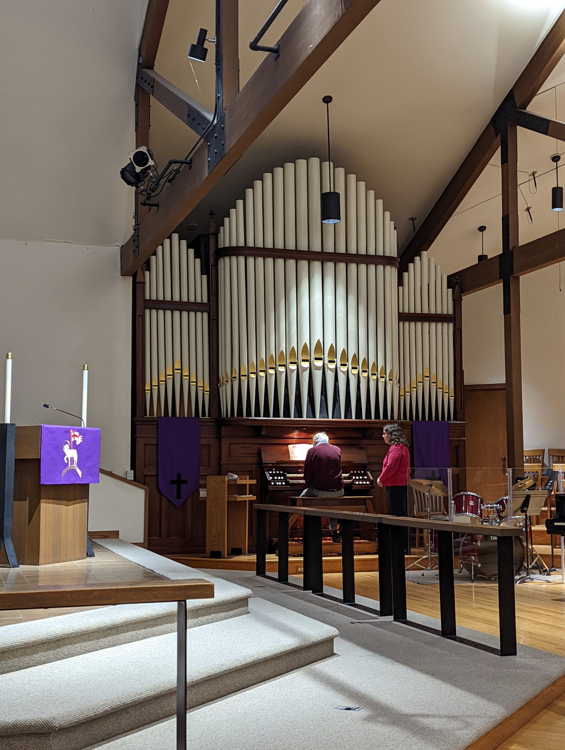 Tim Drewes playing the organ while Cheryl Drewes stands to the side assisting with registration