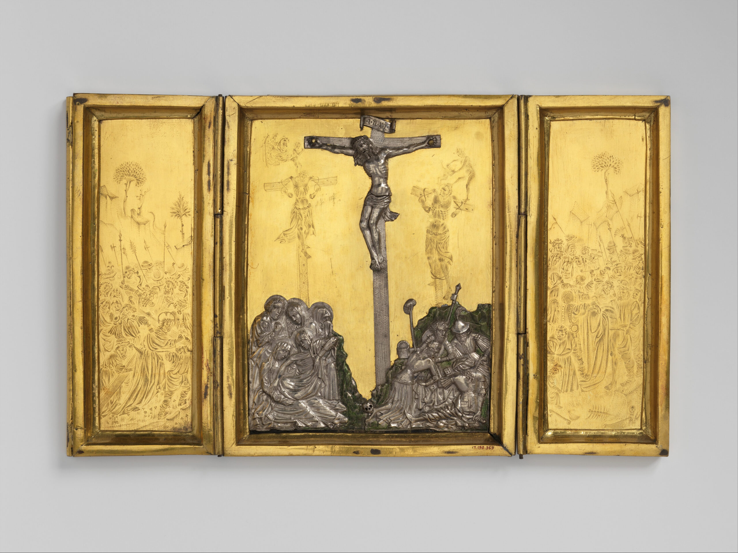 A gold triptych with the center panel showing the Crucifixion