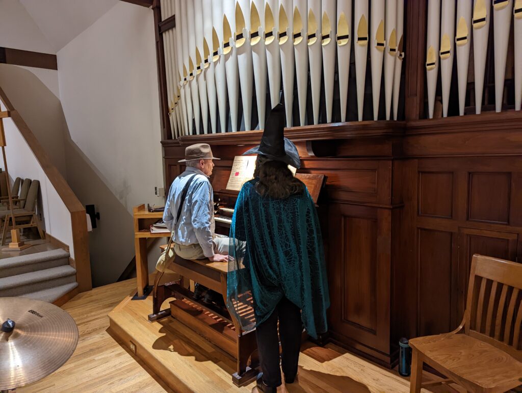 Man playing an organ in costume with woman in costume assisting