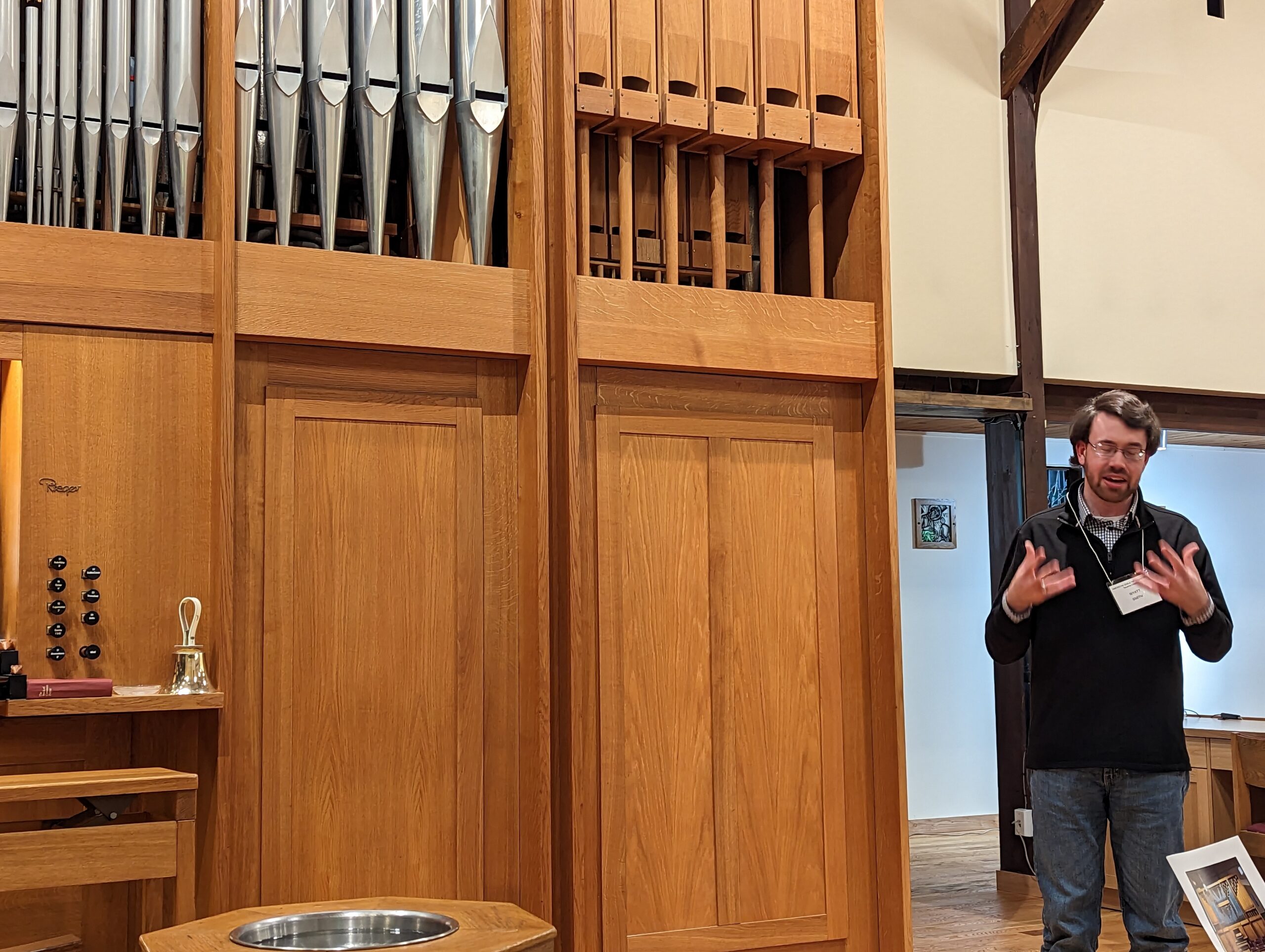Man standing in front of an organ speaking to an audience