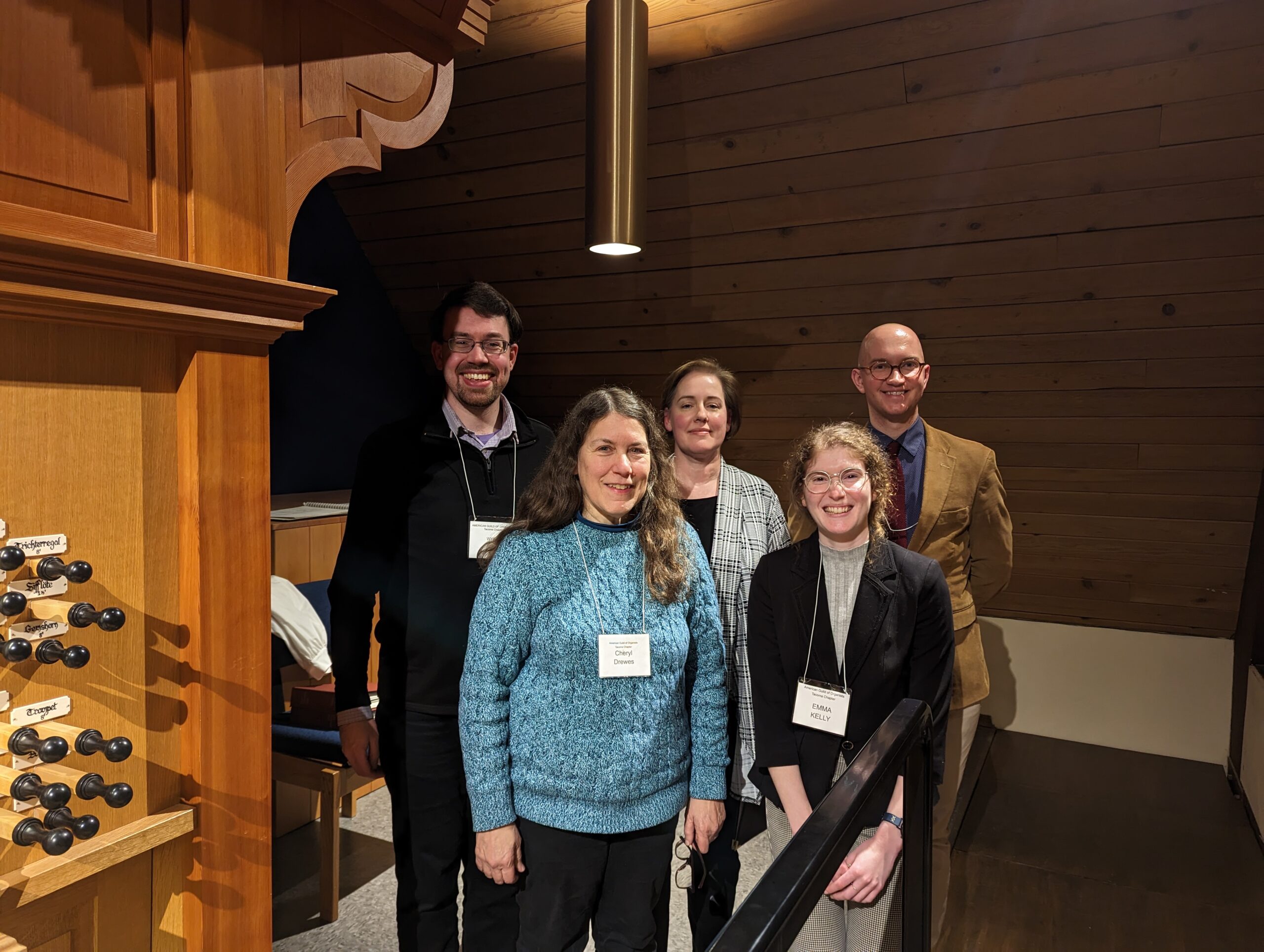 Group of 5 people posing beside organ