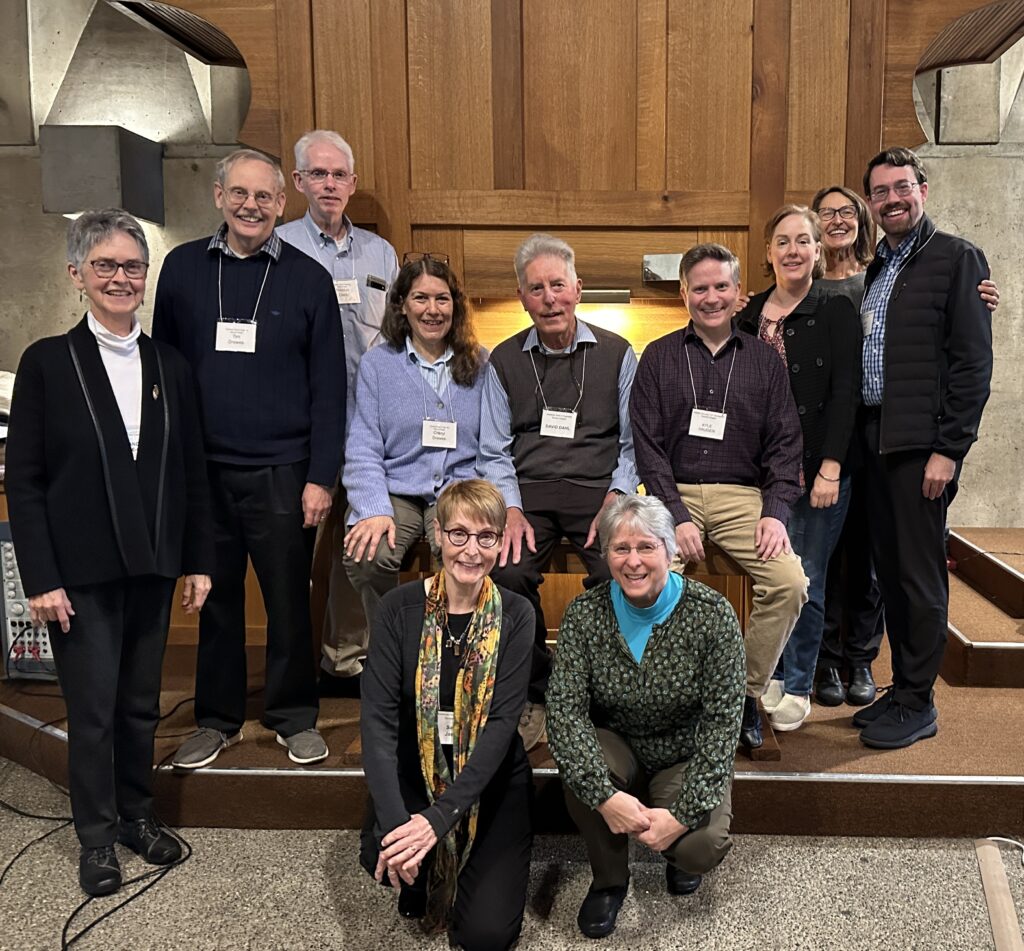 group of people posing in front of organ