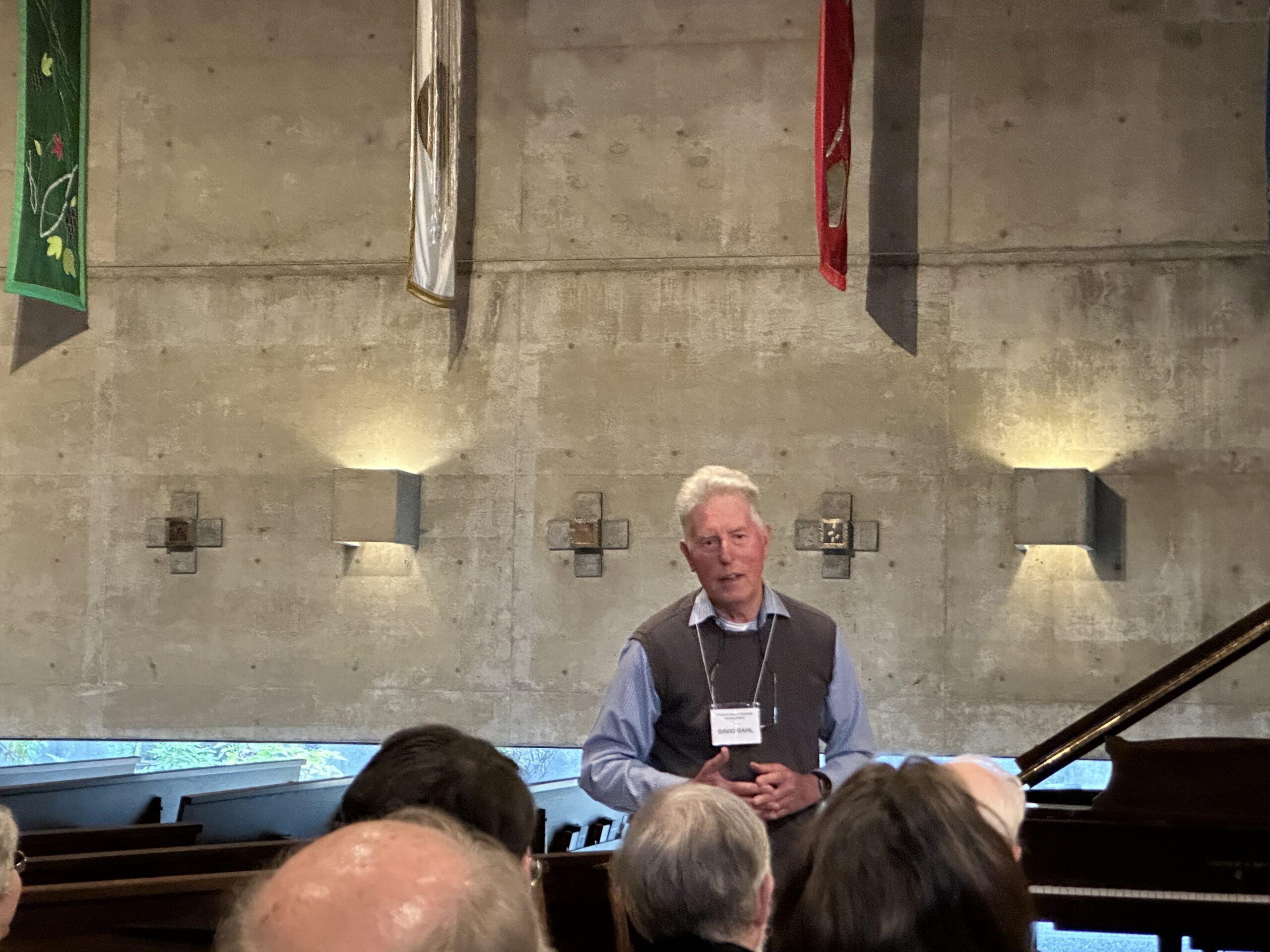 man with name tag stands beside piano