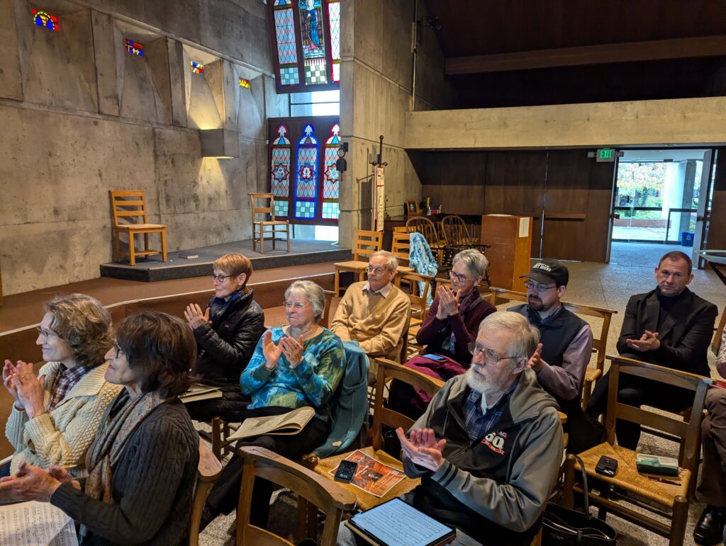 A group of people seated in a church applauding.