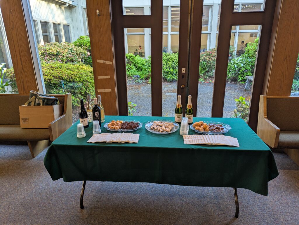 A table in the narthex of a church with cookies, pastries, and bottles of wine